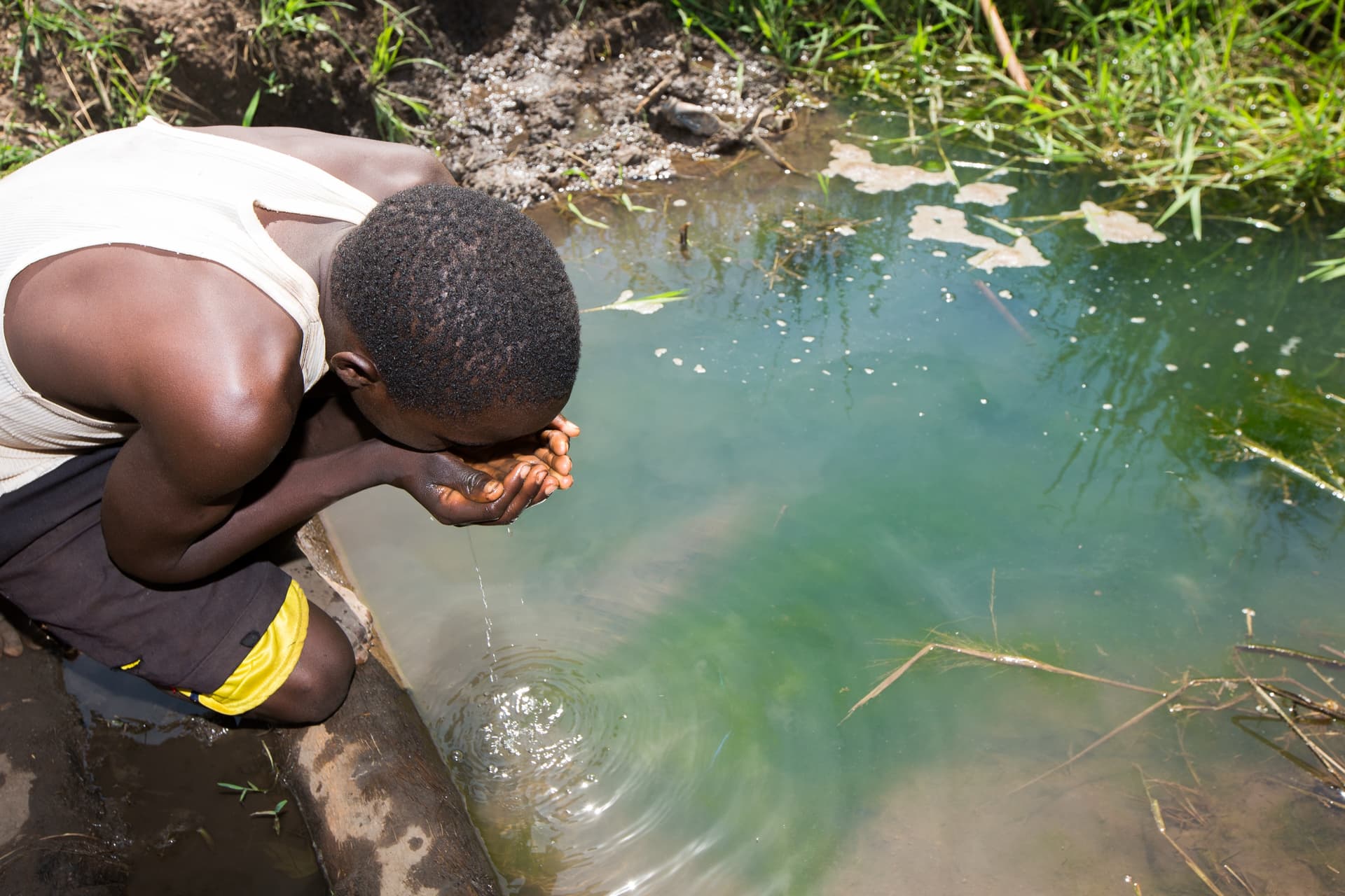Child drinking from contaminated water source